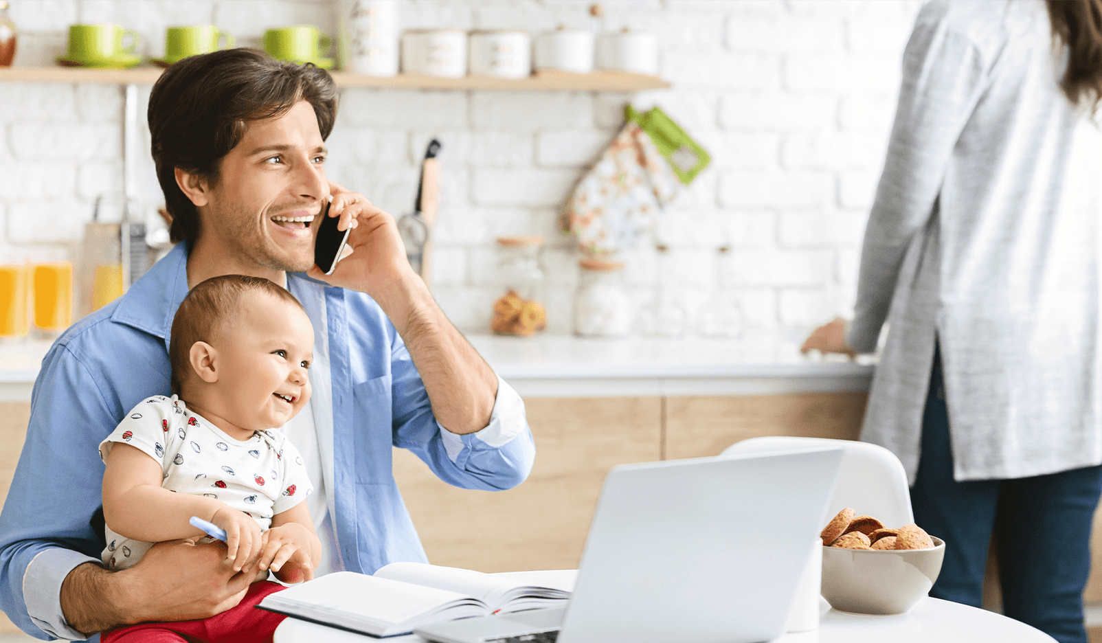 man working from home while taking care of his child